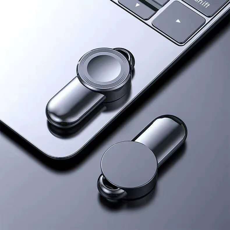 A white USB wireless charger with a thin profile, positioned next to a laptop on a desk.